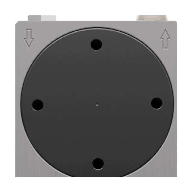 The front of a turbine vibrator: a large round black cover filling nearly the whole front face of the body. Four through holes sit near the rim of the cover, one at the top, one at the bottom and one on each side, and a small mark sits at its centre. To the left and right of the cover an arrow is cast into the front face.