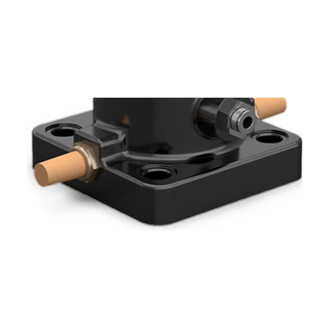 Close-up of the foot of the largest continuous impact vibrator: an almost square black plate with counterbored holes in the corners, a brass silencer on each side, one of them screwed into the foot itself, and the body rising from the middle of the plate.