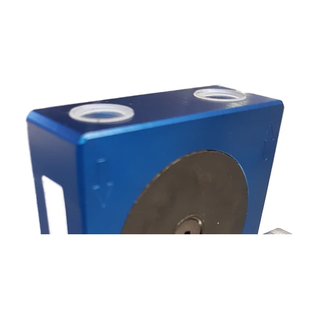 The top face of a blue anodised ball vibrator with two threaded ports with bright rings, one at each end. An arrow is cast into the front face under each port: the left one points down, the right one up. At the bottom the edge of the dark cover is visible.
