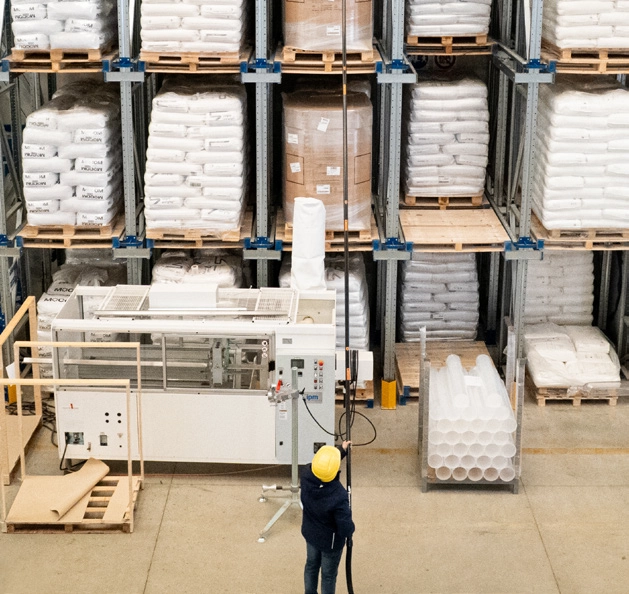 Operator using CleanUp system to clean high warehouse shelving without a lift